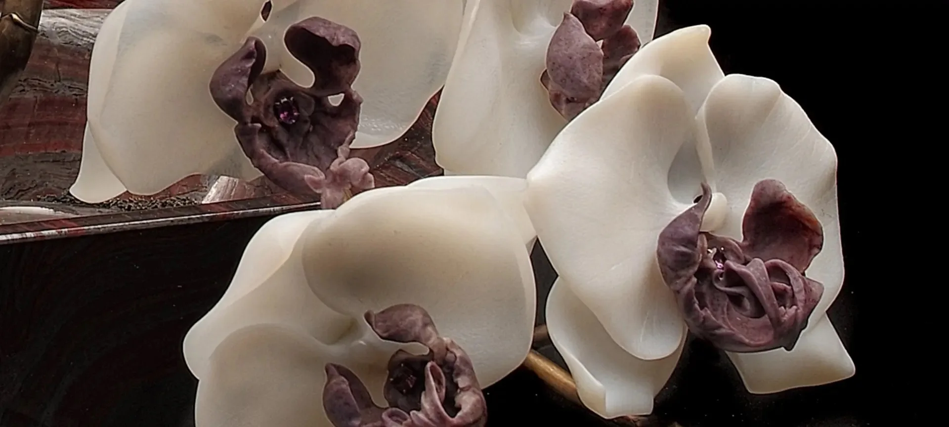 Fine texture across white orchid petals and carved burgundy centers.